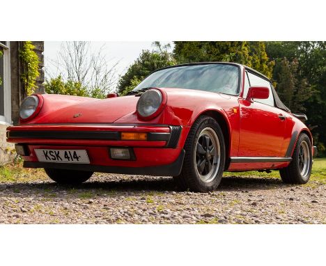 A 1985 Porsche 911 convertible sports car, 3164cc engine, guards red livery, black canvas tonneau, black leather interior wit