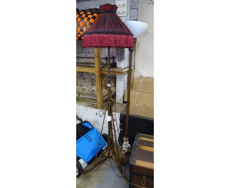 An Art Nouveau iron standard lamp, converted to electricity, with tasseled shade, and an early 20th century cast-iron standar