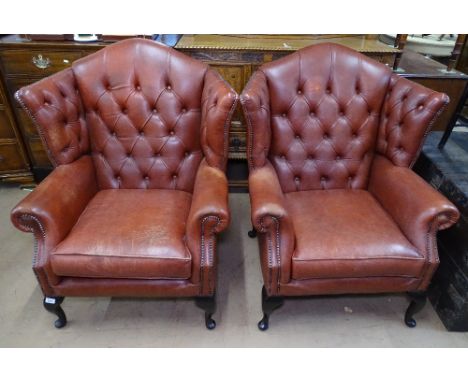 A pair of Thomas Lloyd button-back leather-upholstered wing armchairs, on cabriole legs 
