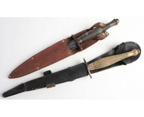 Two Fairbairn Sykes pattern knives: one with chequered brass grip in black leather scabbard, the other with ribbed grip in br