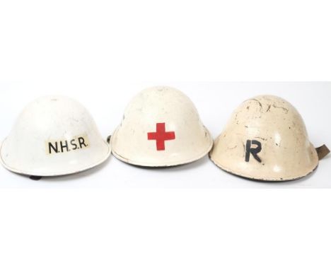 A post war National Health Service Reserve Mk III 'turtle' steel helmet: white with 'NHSR' to front, together with two other 