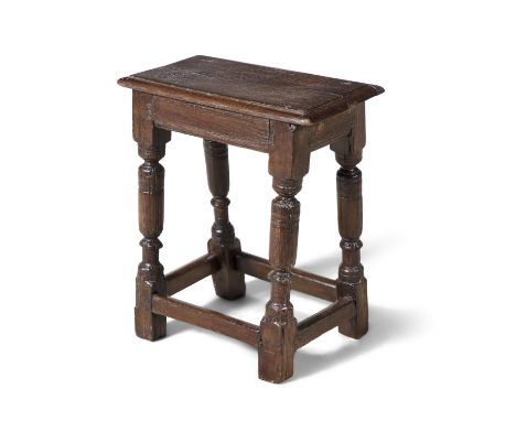 AN 17TH CENTURY OAK JOINT STOOL, with moulded panel seat, on four splayed column supports, joined by stretchers. 54cm high, 4