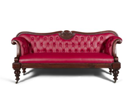 A GEORGE IV MAHOGANY FRAMED SCROLL-END BUTTON BACK SOFA, the serpentine back with carved central crest, upholstered in red le