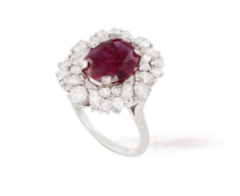 A RUBY AND DIAMOND CLUSTER RING, composed of a central oval-shaped ruby weighing approx. 2.80cts within a four-claw setting a