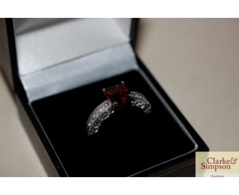 A silver white metal and red stone set ring