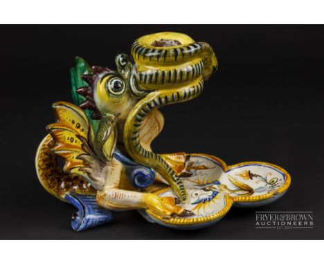 A Cantagalli maiolica grotesque candlestick, formed as a winged beast holding a coiled snake in its mouth to form the sconce,