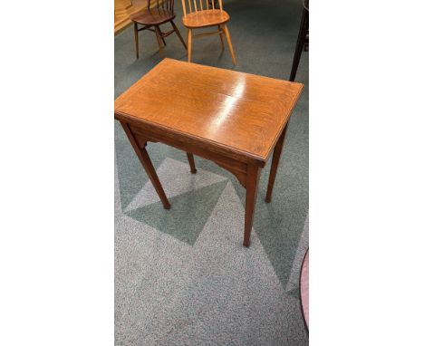 Early 20th-century oak fold-over card table with a green felt surface. Features elegant tapered legs and a hinged top. Classi