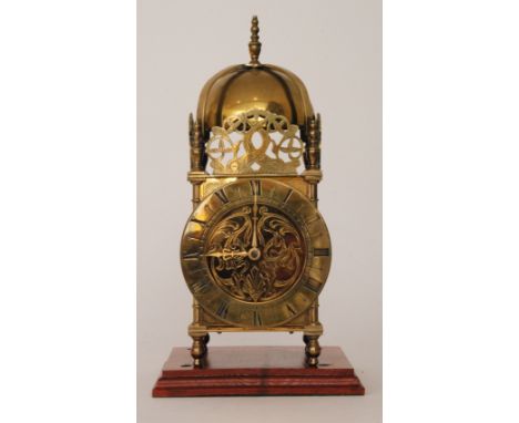 A 17th Century style brass lantern clock with bell over a movement scroll engraved centre on ball feet, height 32cm