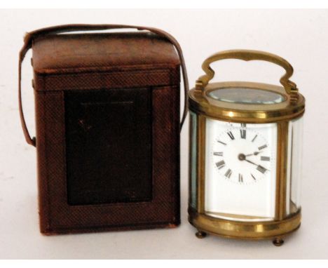 An early 20th Century French oval brass carriage clock white painted enamelled dial on cushion feet with associated leather c