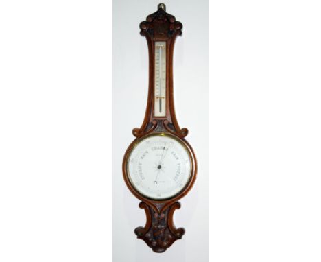 A late 19th Century carved oak aneroid barometer by Woodroffe Stockton on Tees, the white enamel dial below a thermometer, he