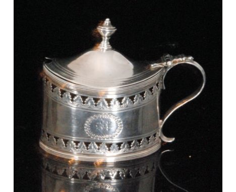 A George III hallmarked silver covered mustard pot of oval outline with pierced foliate decoration, reeded borders terminatin