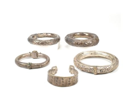 A collection of five white metal bangle bracelets to include a Yemeni Bedouin bangle, two African Omani rattle bangles, an In