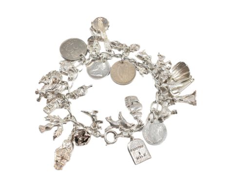 A silver charm bracelet. The silver charm bracelet having 28 charms strung on a curb link chain with a spring ring clasp. Cha