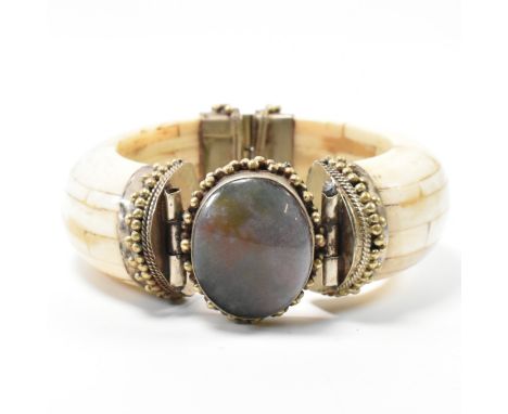 A vintage 20th century Indian cuff bangle bracelet. The bangle bracelet decorated with an oval shaped stone in the middle wit