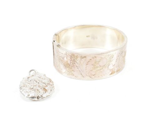 A hallmarked silver hinged bangle together with a hallmarked silver necklace pendant. The lot to include a hallmarked silver 