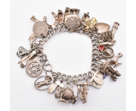 A hallmarked silver charm bracelet. the bracelet strung with multiple charms including fish shoes, pixie, church, birdcage, h