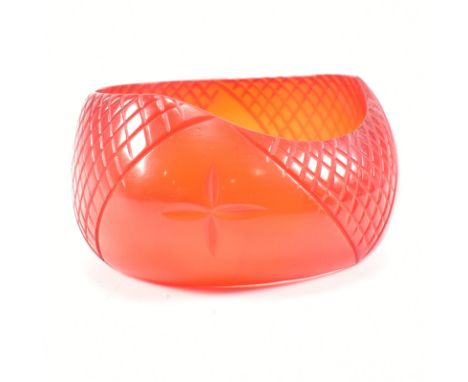 A vintage red carved Lucite bangle. The bangle having carved crosshatched decoration with flower motif. Measures internal dia