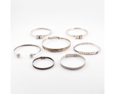 A collection of silver and gem set bangles. The lot to include two silver bangles with bow decoration set with round cut blac