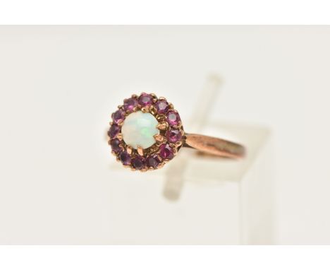 A 9CT YELLOW GOLD OPAL AND RUBY CLUSTER RING, set with an opal cabochon, surrounded by rubies, to the plain polished band, ha