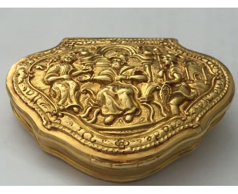 A C17th/ C18th Gold snuff box with embossed decoration depicting three figures the central figure seated adorned with script 
