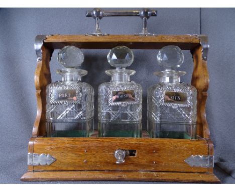 THREE BOTTLE TANTALUS with stoppers and white metal labels for port, whisky and gin