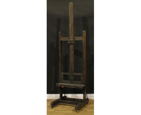 A 19th century artist's studio painting easel, adjustable on a pulley system, H-shaped base, wooden casters, 225cm high, 63cm
