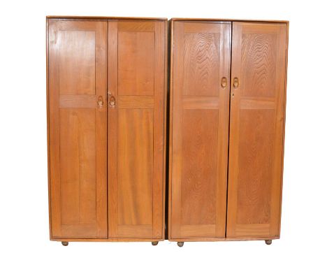Near pair of Ercol light elm narrow wardrobes, each fitted with a hanging rail, raised on ball casters, width 91cm depth 55cm