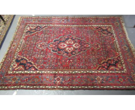 Middle Eastern design red ground carpet with central lozenge medallion flanked by flowers, foliage and geometric decoration. 