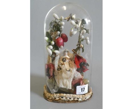 A ceramic shoulder head doll and wax fruit diorama, the doll with painted features and bisque arms under an arch of fruit and