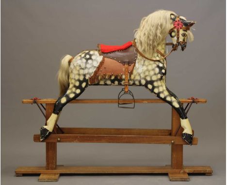 A wood carved rocking horse by Collinson, first half of the 20th century, with metal button eyes, painted features, dappled g