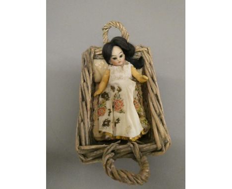 An oriental bisque socket head doll's house doll, with brown glass fixed eyes, closed mouth, composition jointed body with mo