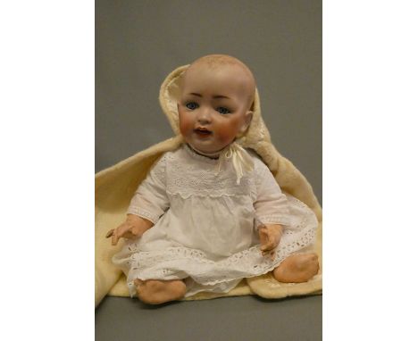 A bisque socket head character baby doll, with blue glass sleeping eyes, open mouth, teeth and integral tongue, moulded hair,