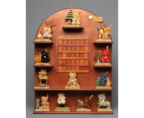A Steiff perpetual calendar, comprising a wooden arched and shelved display, with central calendar and a collection of twelve