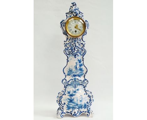 Continental Ceramic Clock - A circa 1900 timepiece with circular dial and convex glass in a tall faience blue and white case 