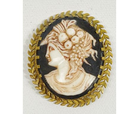 Cameo - A gilt metal laurel chaplet bordered black hard ceramic oval with bust head in profile of a classical lady with fruit