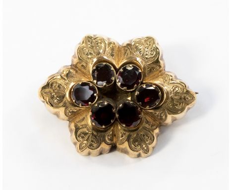 A Victorian yellow metal mourning ring set with six oval garnets surrounded by gold engraved foliate sections, with a hair wi
