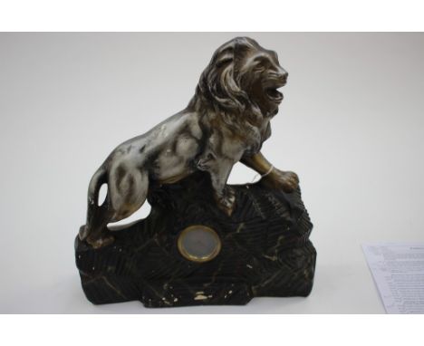 A ceramic mantle clock in the form of a painted silver lion on a black painted outcrop of stone 