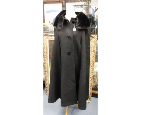 A black wool cape with fur collar. The cape is designed by the Danish born designer  I B Jorgenson who is renowned, especiall