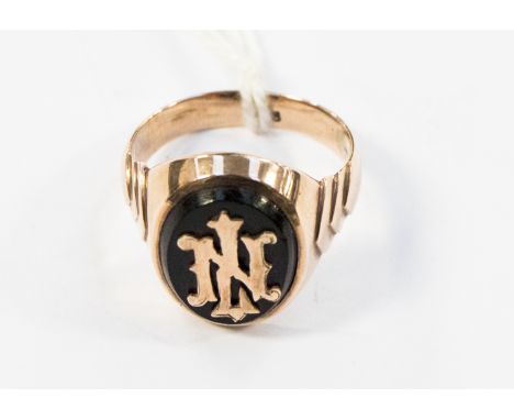 A gentlemen's oval signet ring set with a black onyx and overlaid gold the initials L.N., with chevron shaped shoulders, size