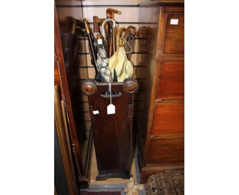 An oak stick stand; together with walking sticks and canes, umbrellas and shooting sticks to include a walking cane, with a b