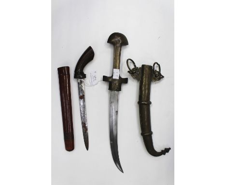 An Arabian dagger with curved 22cm blade with Arabic inscription. All brass grip with decoration. Complete with brass scabbar