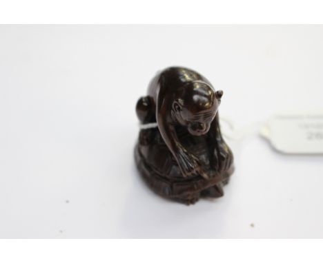 A Japanese dark wood carved Netsuke, depicting a Monkey sitting on the back of a Tortoise, signed to the base 