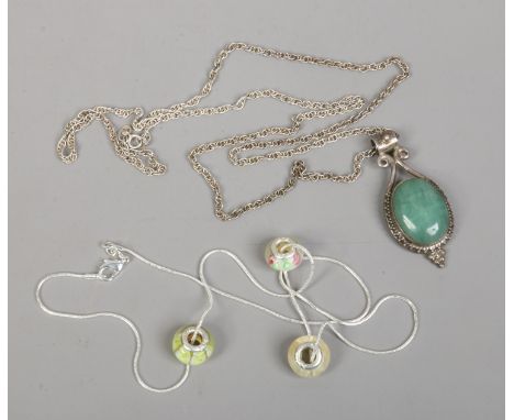 A silver pendant and chain set with a jade coloured hardstone along with a silver necklace and charms.