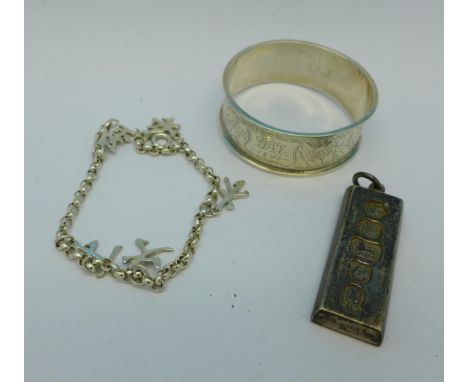 A silver ingot, a silver napkin ring and a silver charm bracelet, 47g