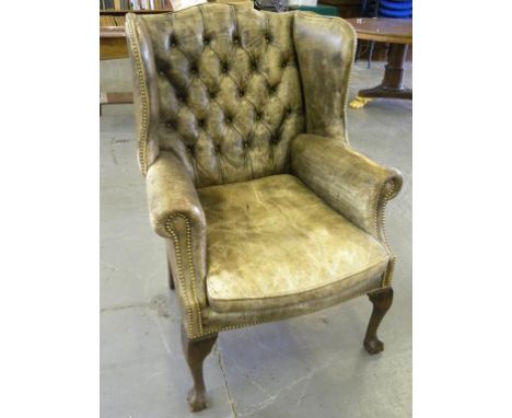A GEORGE II STYLE WING ARMCHAIR UPHOLSTERED IN CLOSE NAILED FADED GREEN HIDE, WITH CUSHION 