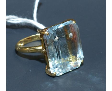 A yellow metal ring set with a large aquamarine coloured cushion cut stone, stamped '750', 8.7 gm