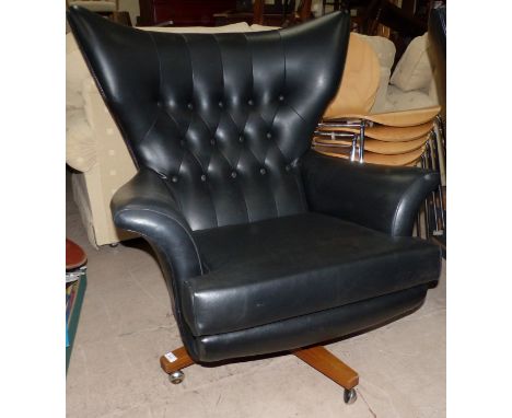 A 1960's G-Plan low swivel armchair in deeply buttoned black leather effect (as Collectors’ item only)