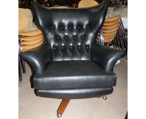 A 1960's G-Plan low swivel armchair in deeply buttoned black leather effect (as Collectors’ item only)
