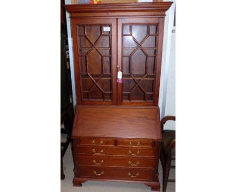 A Georgian style miniature reproduction bureau/bookcase, 2 glazed doors over fall front, 3 long and 2 short drawers, on brack