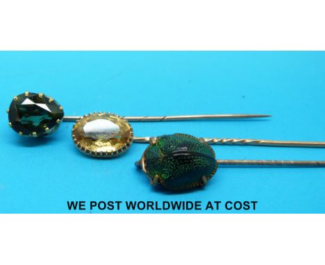 A yellow metal stick pin set with a scarab beetle, and two yellow metal stick pins set with citrine and peridot 